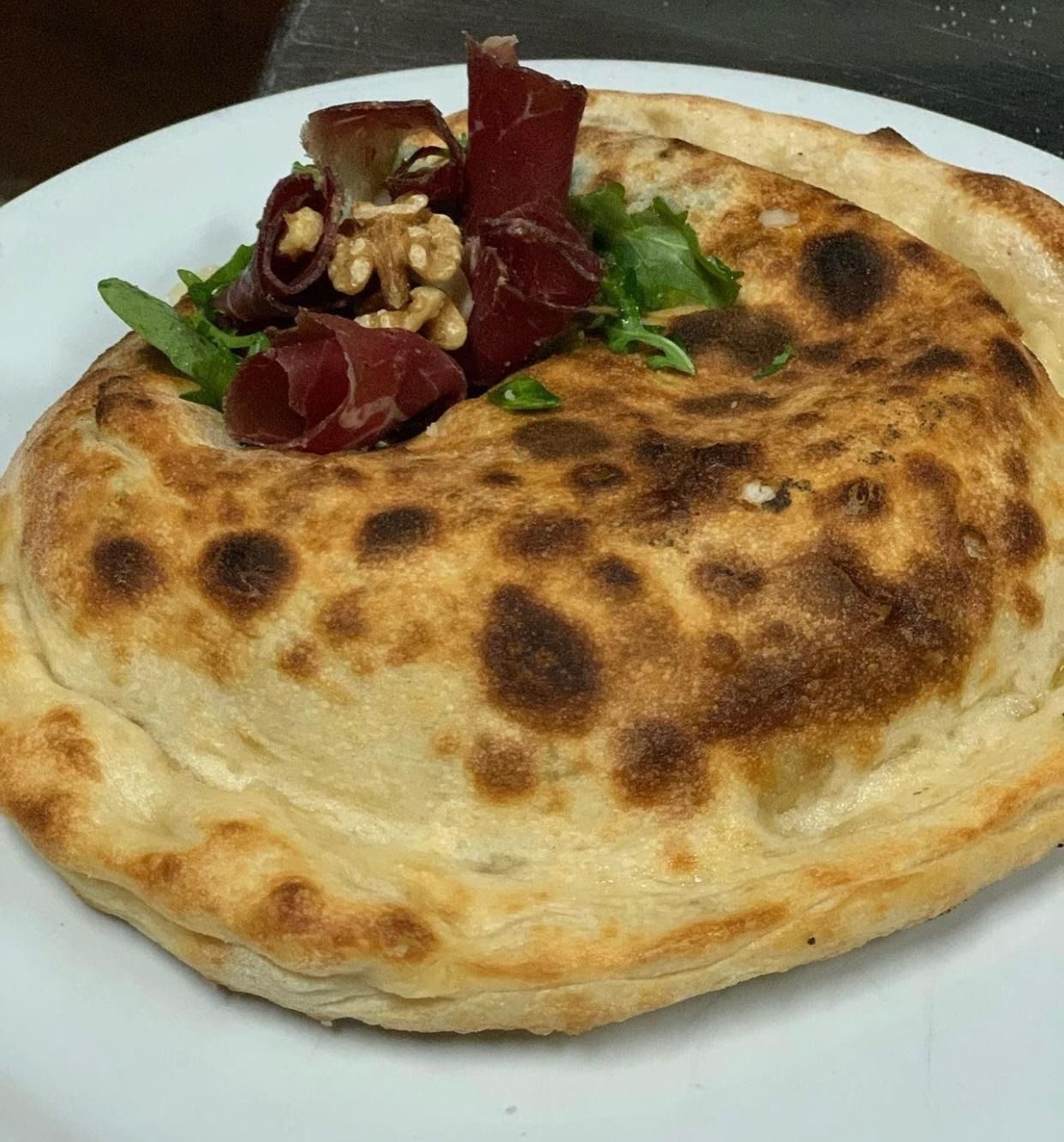 Focaccia ripiena dorata, guarnita con verdure e cipolla rossa.
