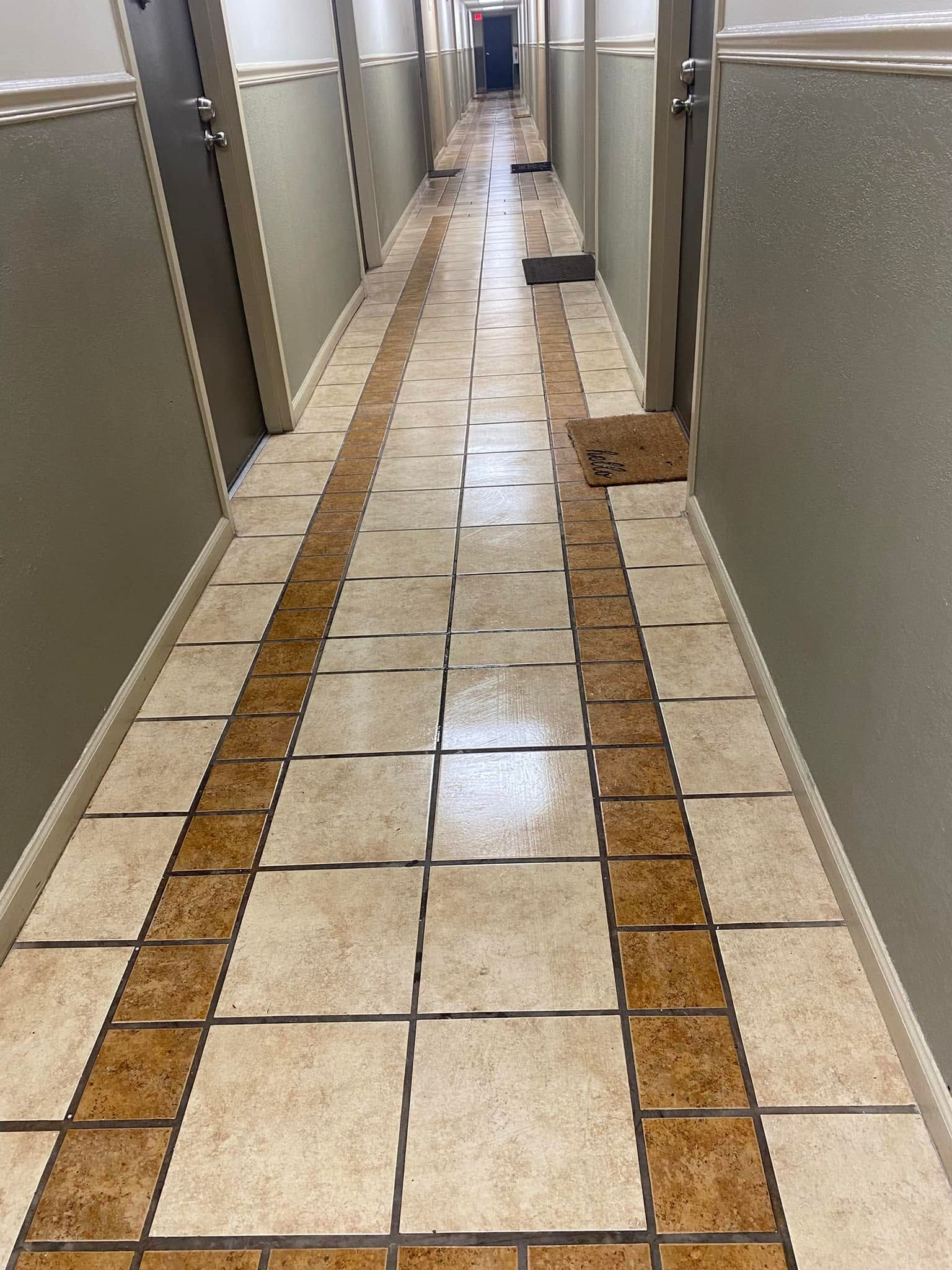 Long tiled hallway with doors on both sides and a brown tactile guide path down the center.