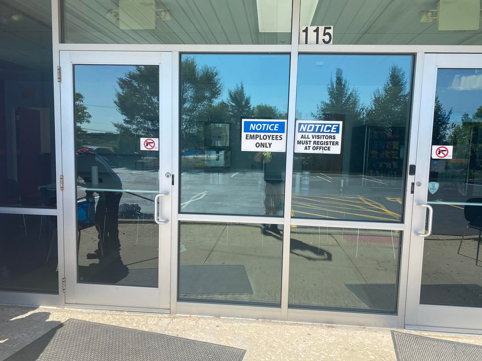 Glass storefront entrance with double doors, handicap signs, and building number 115.