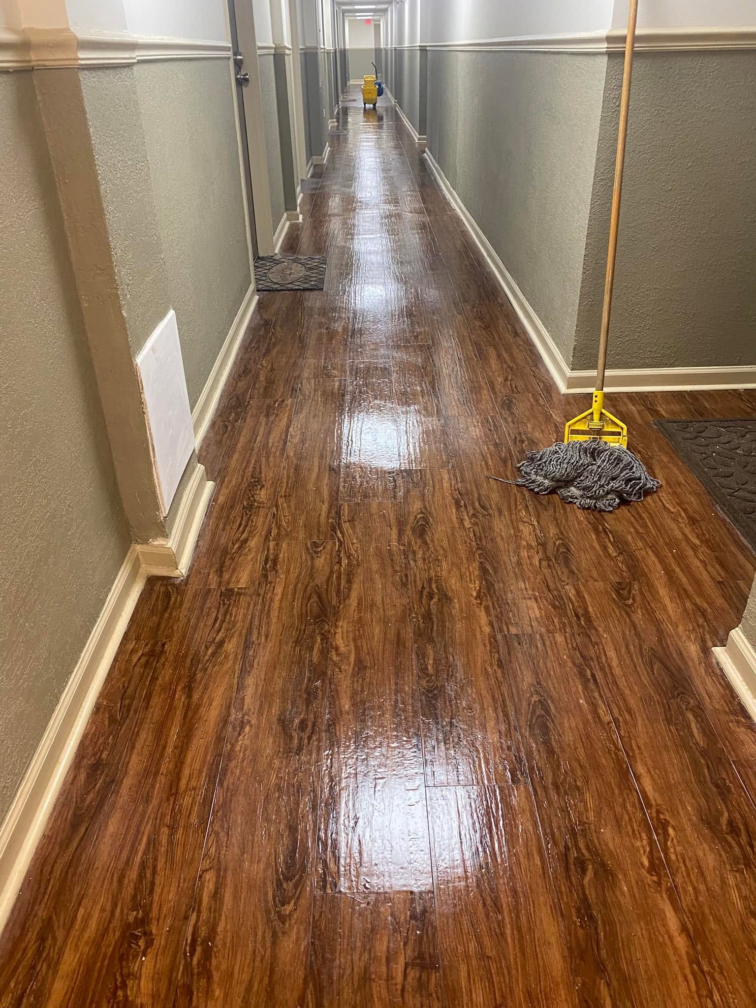 Wet hallway floor with reflections and a caution sign near a mop