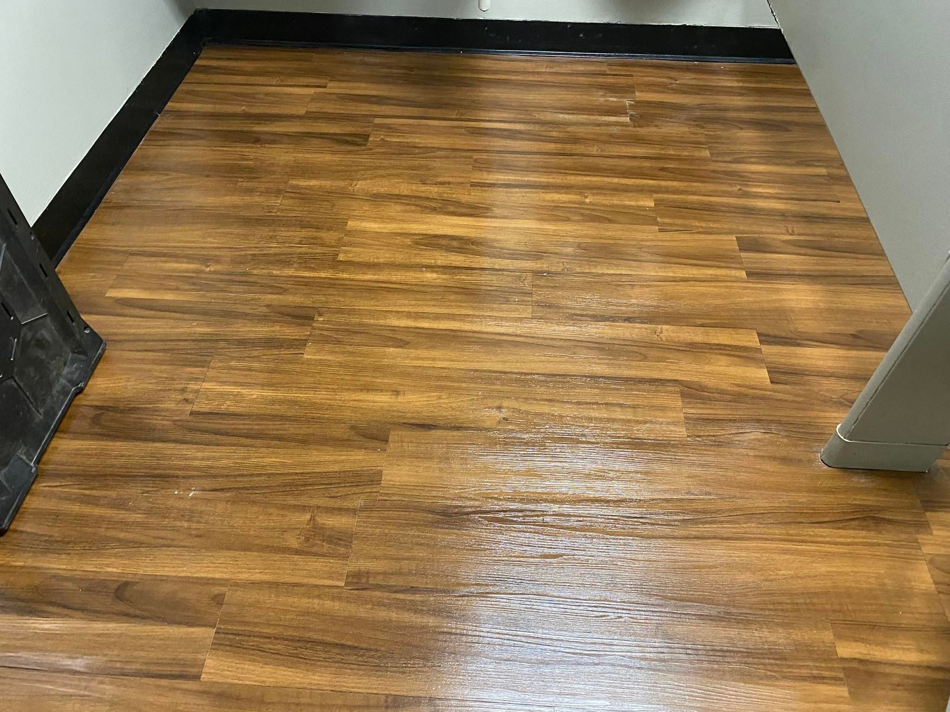 Small empty room with wood-look vinyl flooring and black baseboards