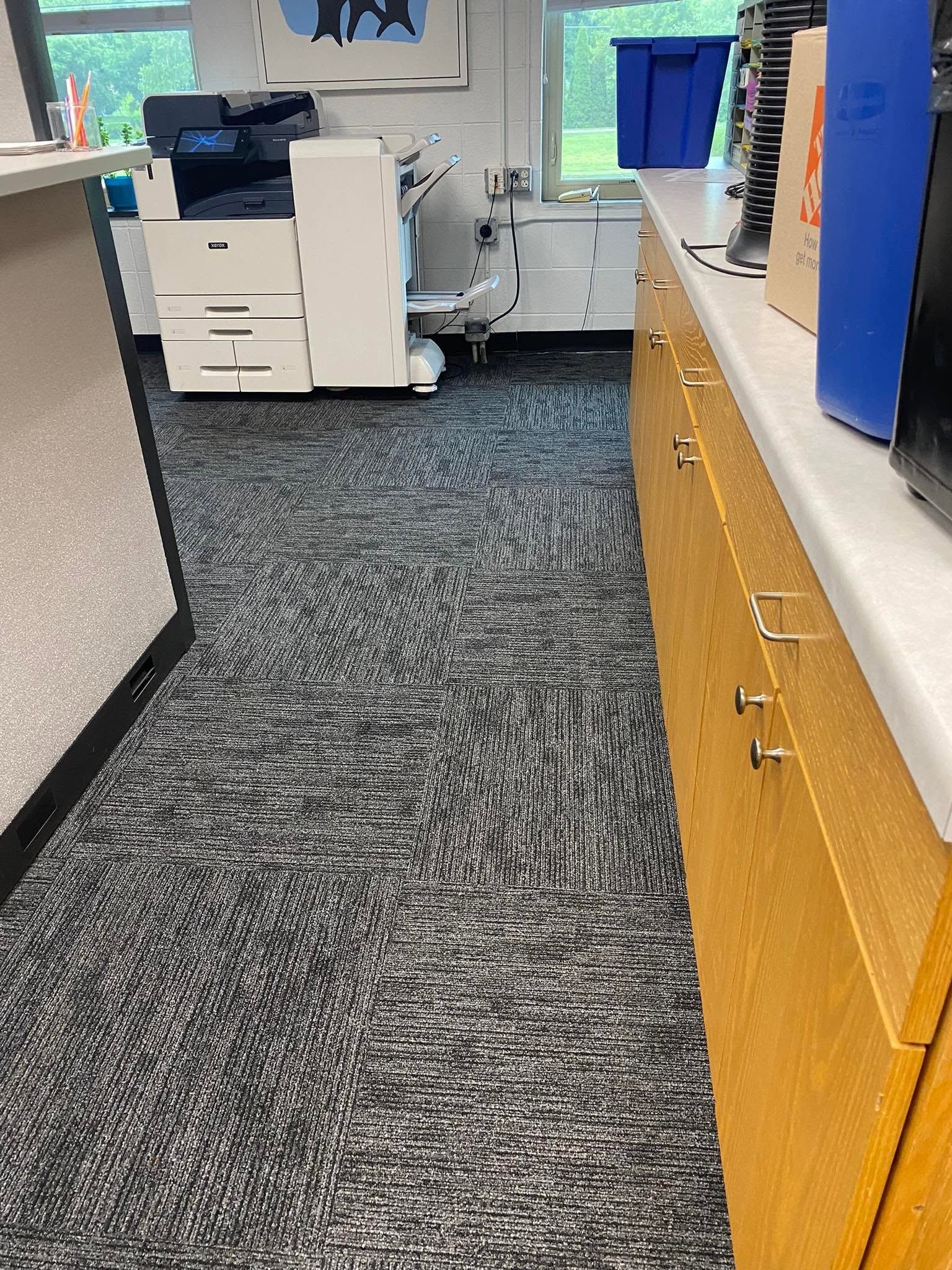 Office hallway with carpet, cabinets, copier, and windows at the end.
