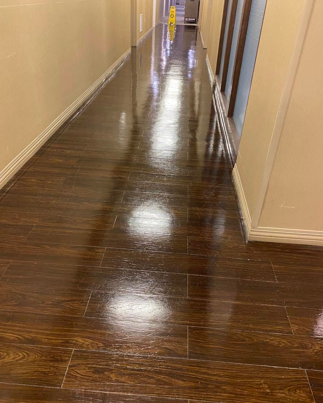 Shiny dark wood hallway floor in a beige corridor with doors on both sides