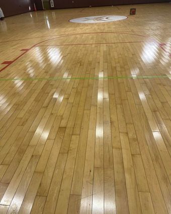 Empty polished gym floor with painted center circle and court lines