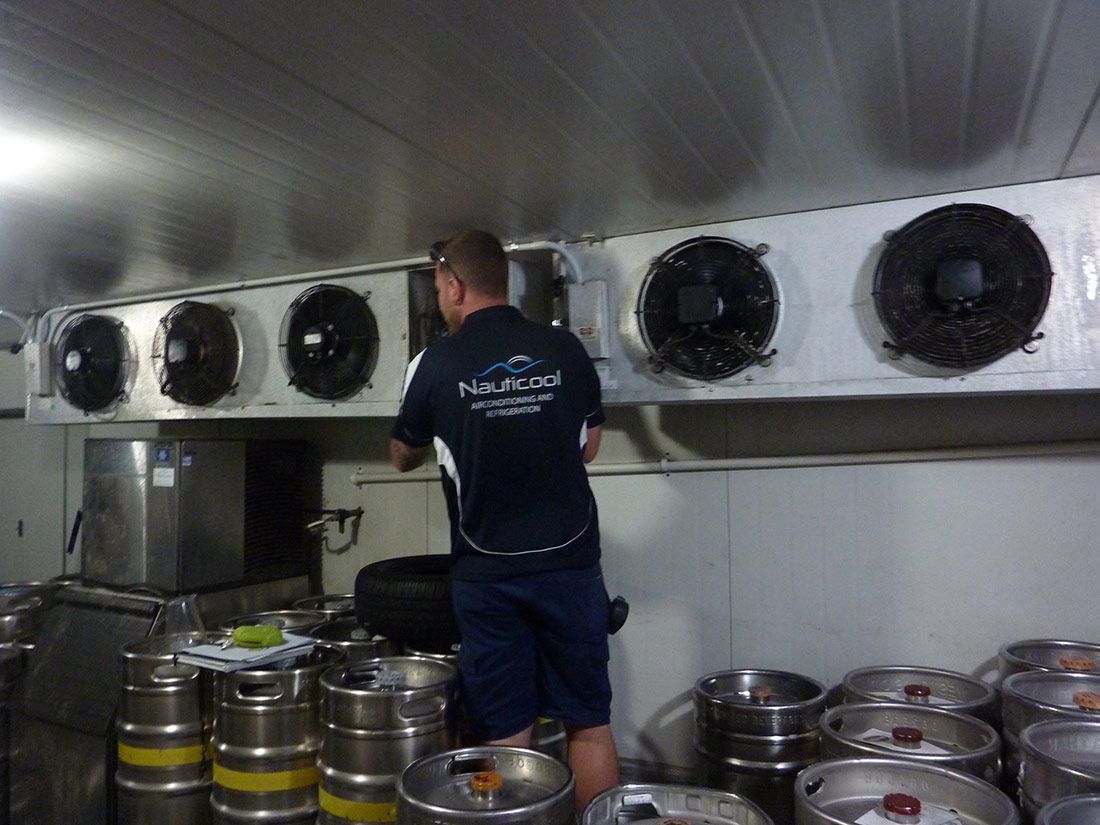 A Man Wearing a Shirt is Working in a Kitchen — Nauticool Refrigeration & Air Conditioning in Cannonvale, QLD