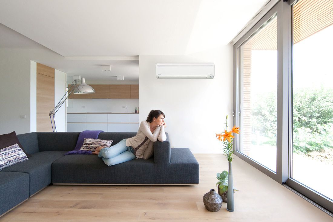 A Woman Laying on a Couch and an Air Condition on the Wall — Nauticool Refrigeration & Air Conditioning in Airlie Beach, QLD