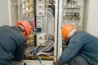 Two Men Are Working on a Electrical Box — Nauticool Refrigeration & Air Conditioning in Cannonvale, QLD