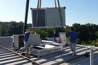 A Group of Men Are Working on the Roof of a Building — Nauticool Refrigeration & Air Conditioning in Cannonvale, QLD