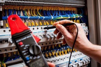 A Person is Using a Clamp Meter to Test a Circuit Board — Nauticool Refrigeration & Air Conditioning in Cannonvale, QLD
