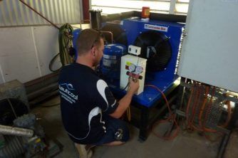 A Man is Working on a Machine in a Room — Nauticool Refrigeration & Air Conditioning in Cannonvale, QLD