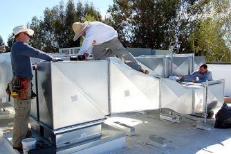 A Group of Men Are Working on a Roof — Nauticool Refrigeration & Air Conditioning in Cannonvale, QLD