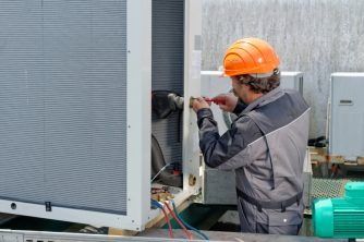 A Man Wearing a Hard Hat is Working on a Machine — Nauticool Refrigeration & Air Conditioning in Cannonvale, QLD