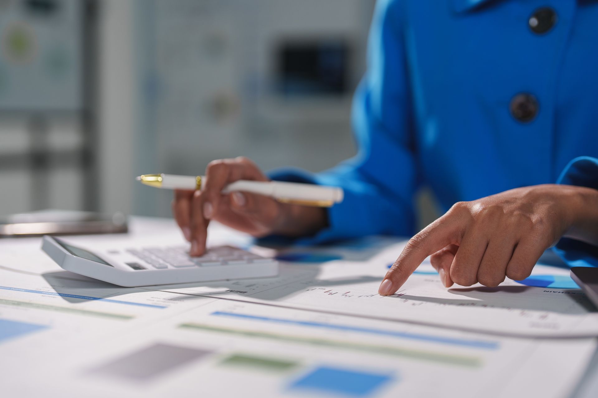 Hands in blue blazer pointing at documents during a business meeting