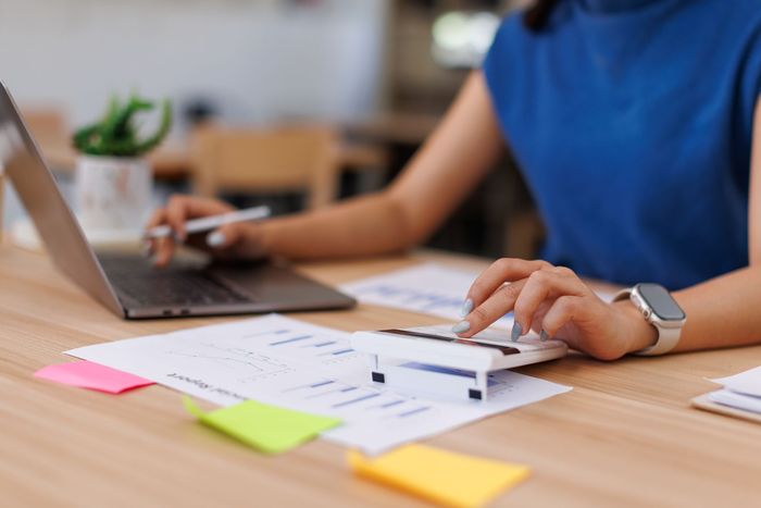 Person working on laptop and papers at a desk with colorful sticky notes