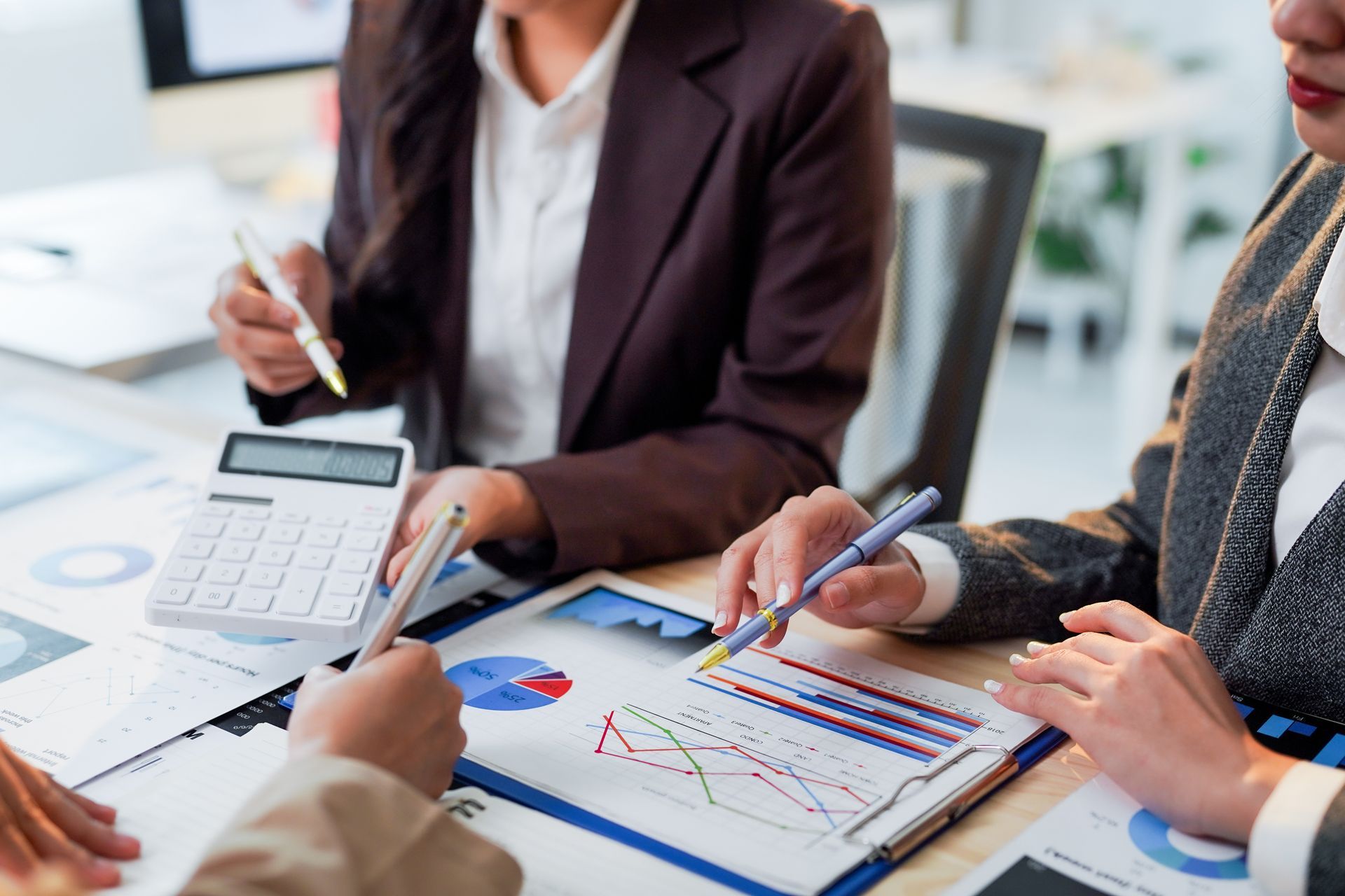 Colleagues reviewing charts and calculator at a desk during a business meeting