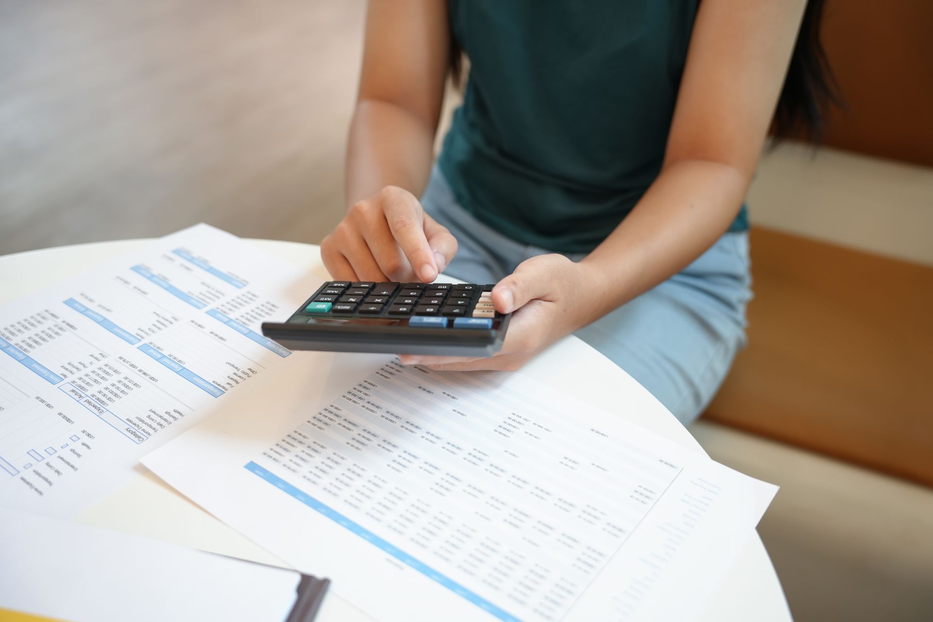 Person using a calculator over paperwork at a desk