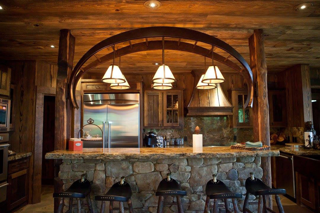 Rustic kitchen with stone bar, wooden beams, pendant lights, and stainless steel appliances.