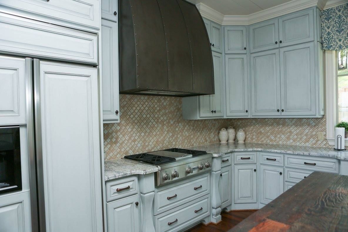 Light blue kitchen cabinets with stainless steel appliances and a metal range hood.