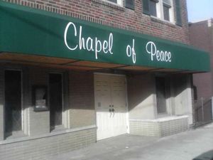 Entrance to Chapel of Peace with green awning and white doors on a brick building