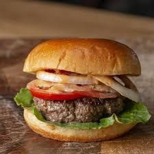 Hamburger on a bun with lettuce, tomato, and onion.