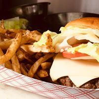 Burger with cheese, lettuce, and tomato, served with fries in a checkered container.