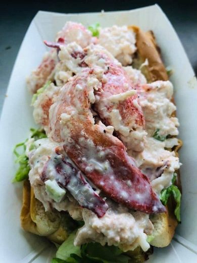 Lobster roll in a white container, with lobster meat, mayonnaise, and lettuce.