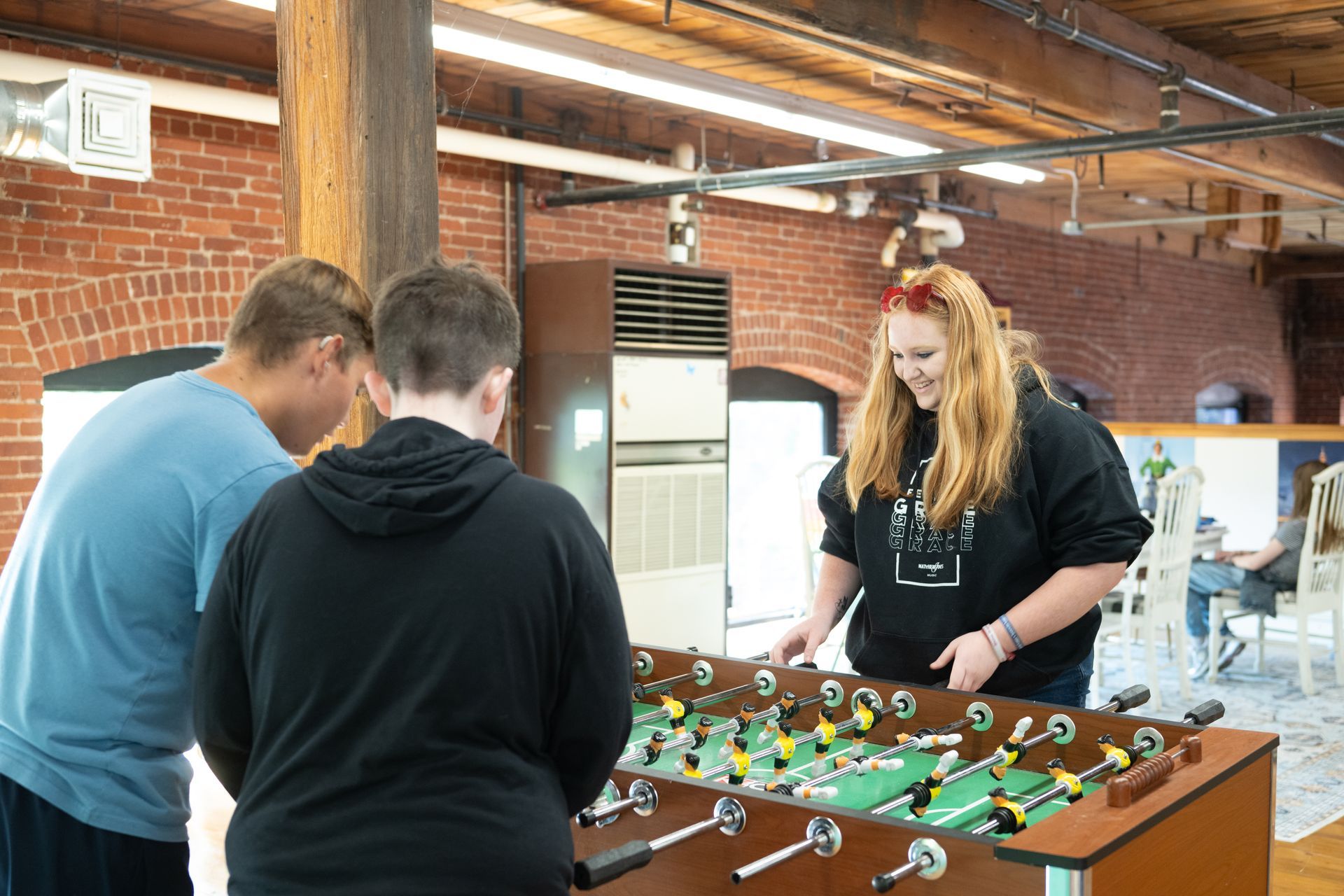 A group of people are playing foosball in a room. A group of people are playing foosball in a room.