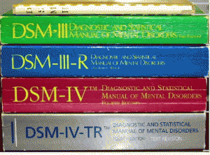 A stack of five Diagnostic and Statistical Manual of Mental Disorders (DSM) books in different colors, arranged vertically.