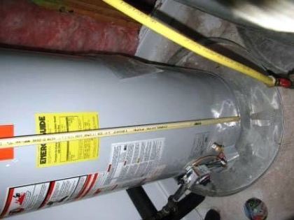 Water heater with yellow gas line and energy guide label, in a basement.