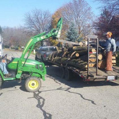 A john deere tractor is pulling a trailer full of logs. A john deere tractor is pulling a trailer full of logs.