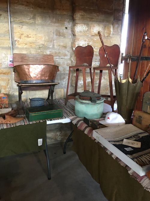 A room with a table , chairs , pots and umbrellas