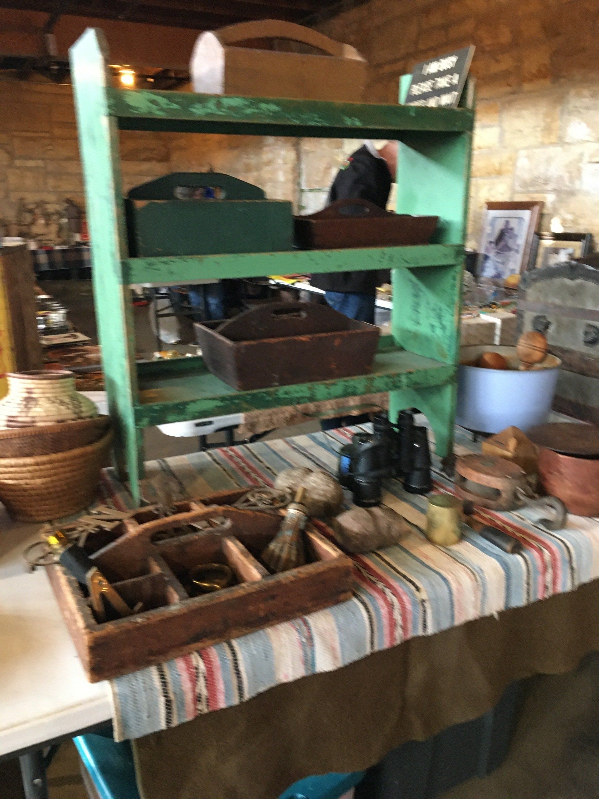 A green wooden shelf is sitting on top of a table.