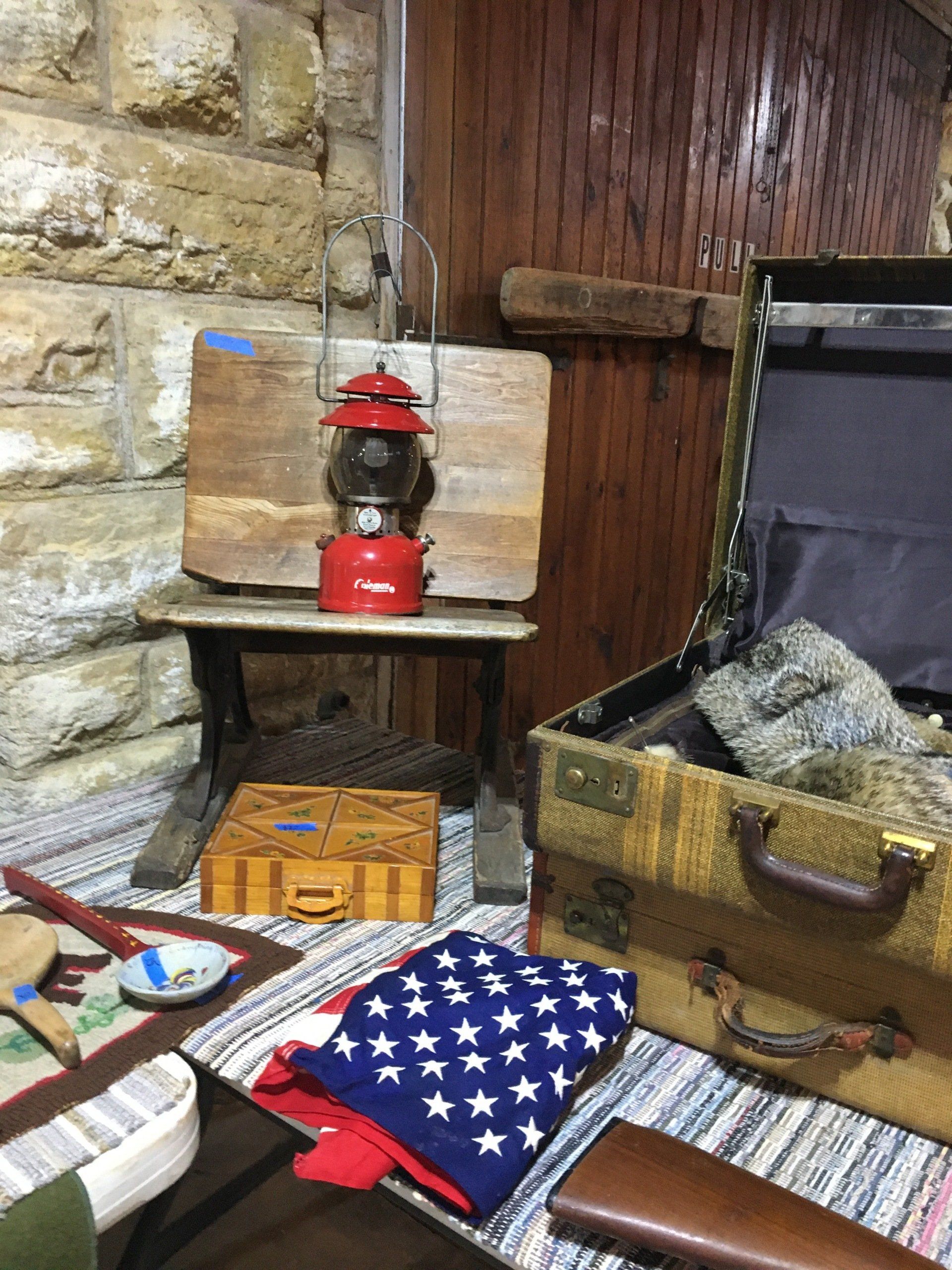 A lantern is sitting on a wooden table next to a suitcase.