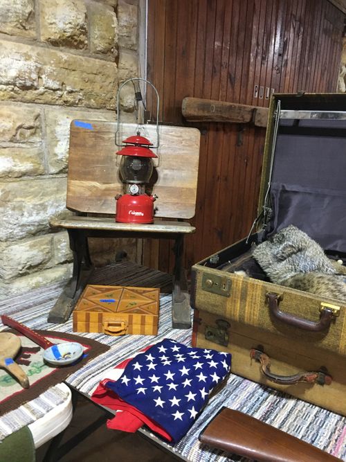 A lantern is sitting on a wooden table next to a suitcase.