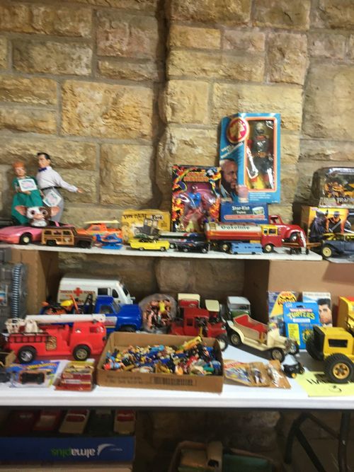 A table filled with lots of toy cars and dolls