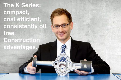 A man in a suit and tie is holding a model of an engine