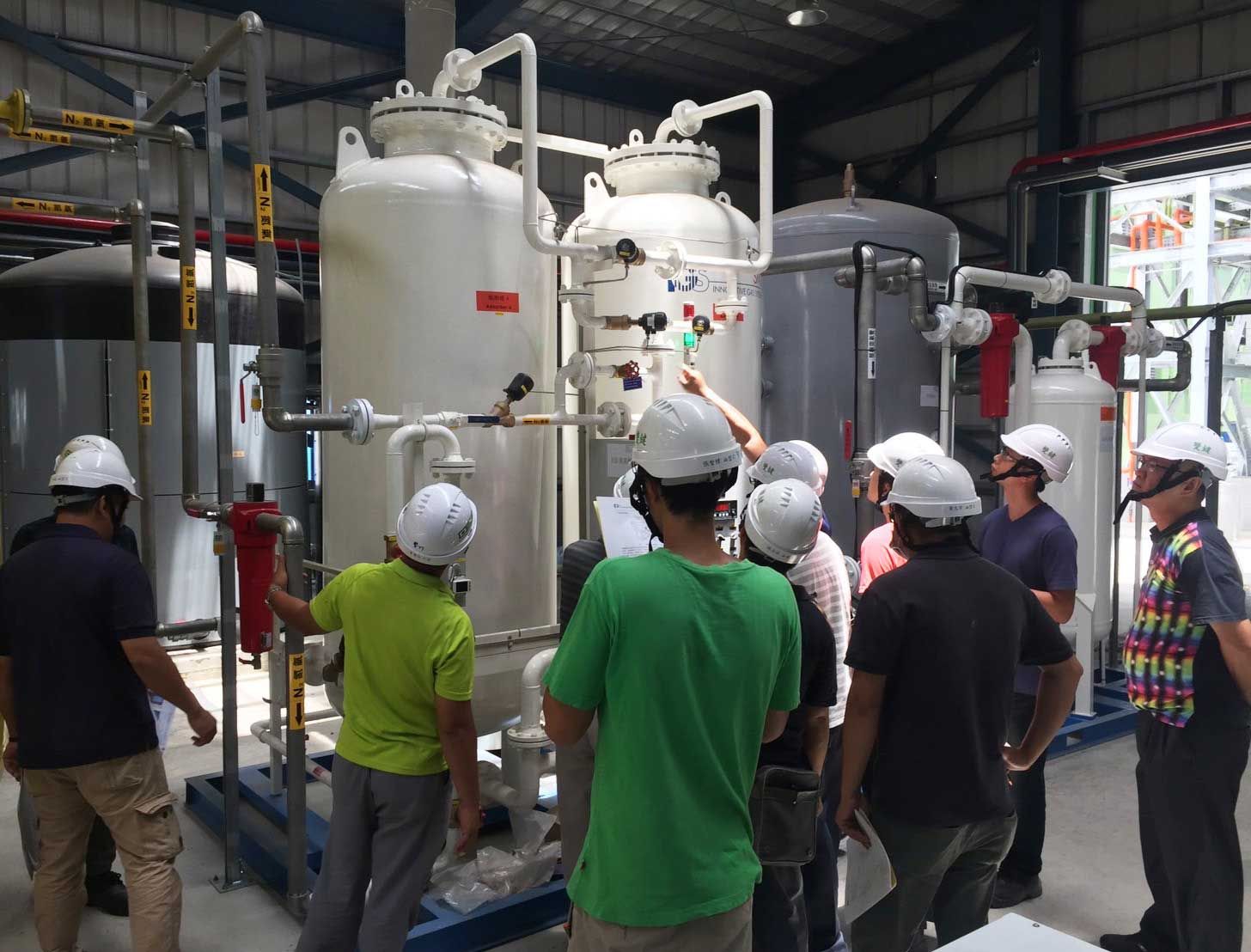 A group of people wearing hard hats are standing around a machine.
