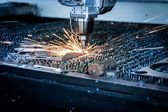 A machine is cutting a piece of metal with sparks coming out of it.