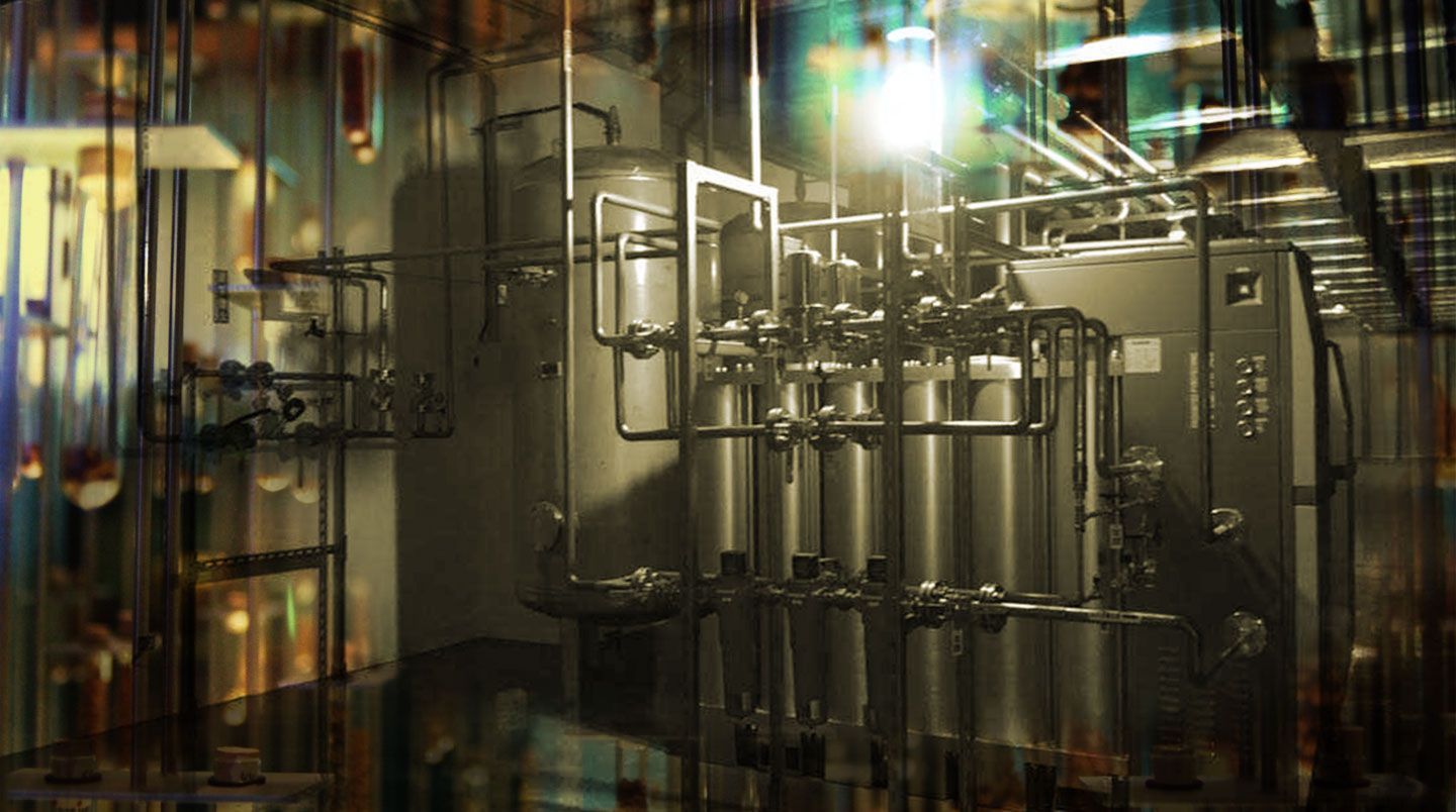 A factory with a lot of pipes hanging from the ceiling.