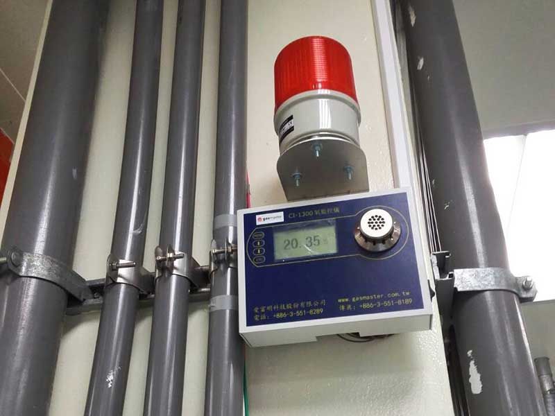 A red warning light is mounted to a wall next to pipes