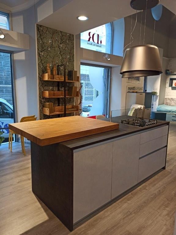 Isola cucina moderna con piano di lavoro in legno, mobili grigi e cappa aspirante in acciaio inox in un interno luminoso
