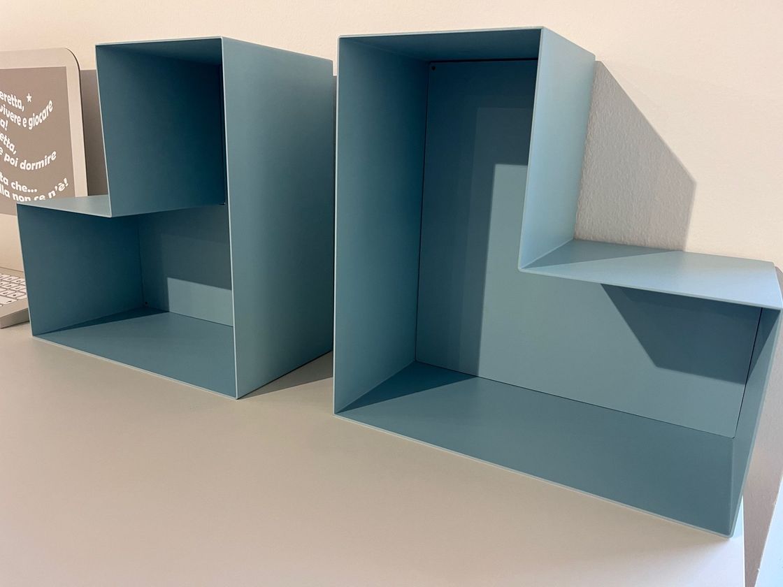 Sculture geometriche di carta blu piegata su una superficie beige