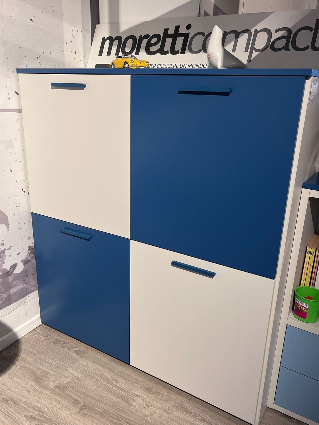 Vetrina a quattro ante blu e bianca in un ambiente espositivo.