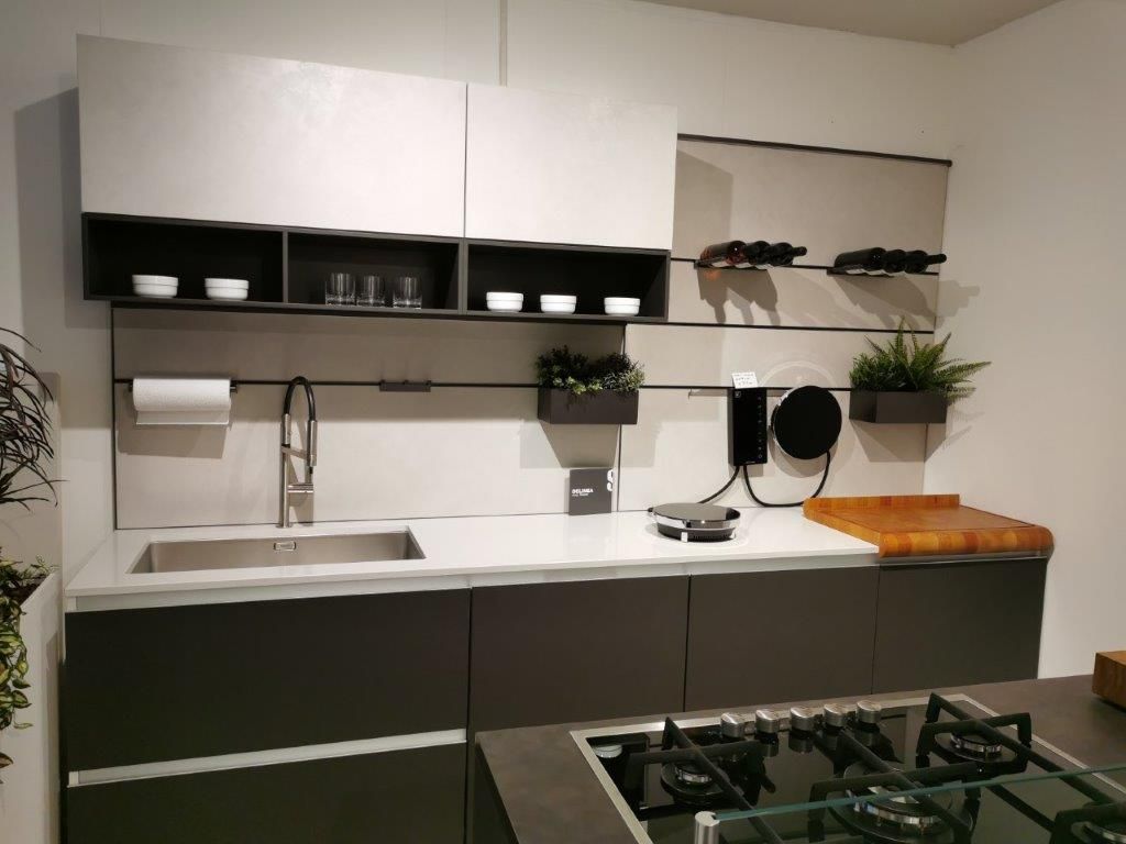 Cucina moderna con pensili bianchi, mobili base scuri, lavello, mensole e piano cottura a gas su un bancone.