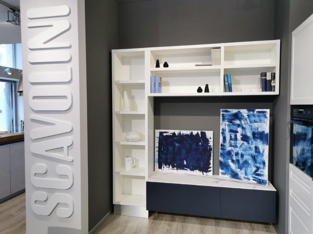 In uno showroom, in posizione elevata, si trovano moderni scaffali bianchi con decorazioni blu accanto a un'insegna verticale con la scritta 