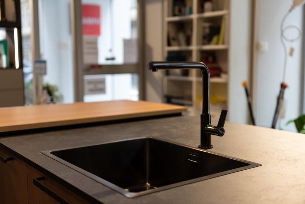Isola cucina moderna con lavello nero e rubinetto nero opaco.