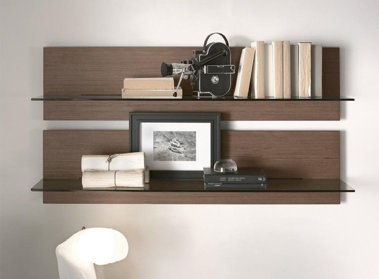 Due mensole a muro in legno scuro con libri, quadri incorniciati e piccoli oggetti decorativi su una parete bianca.