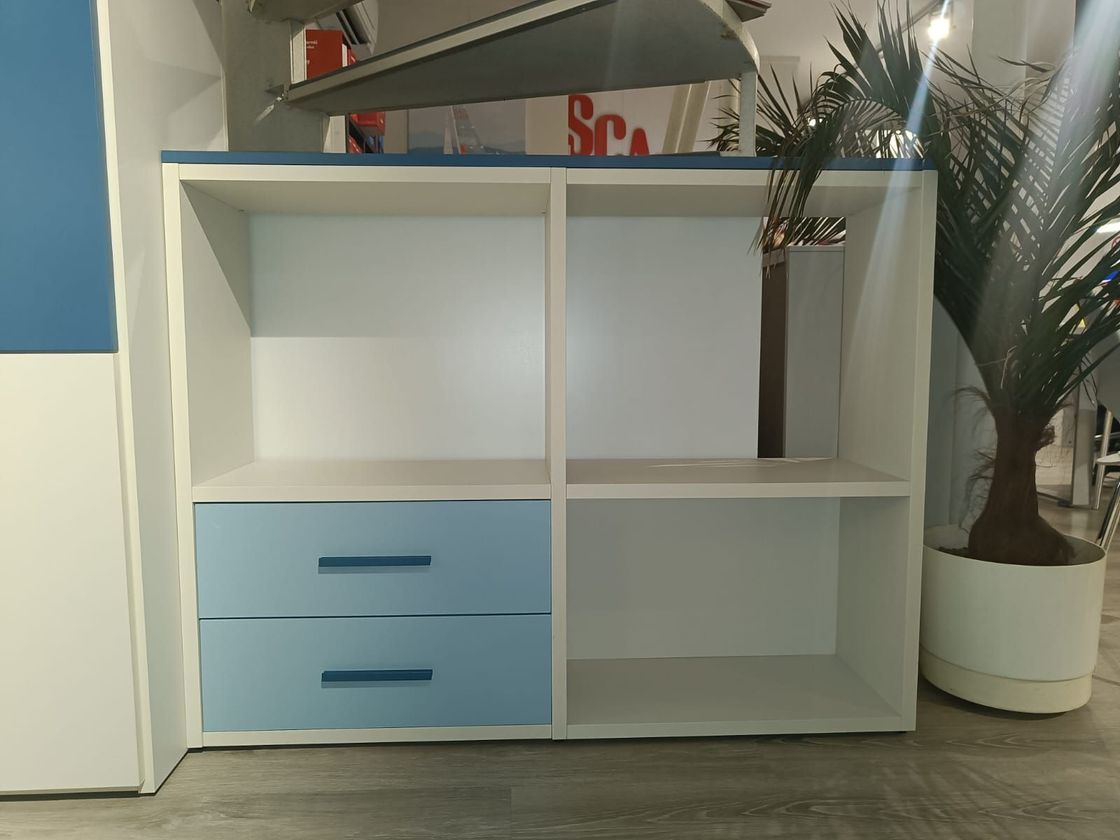 Scaffale bianco con cassetti blu, una pianta alta sulla destra e uno specchio sopra.