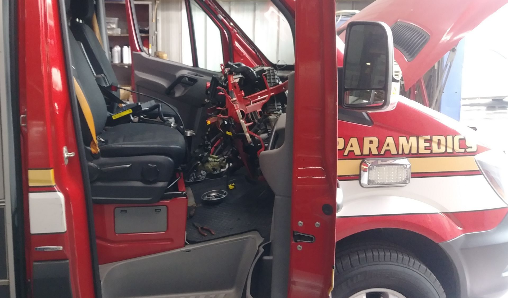 Red paramedic vehicle with open door, showing black seats and equipment inside. | Polar Bear Auto Care