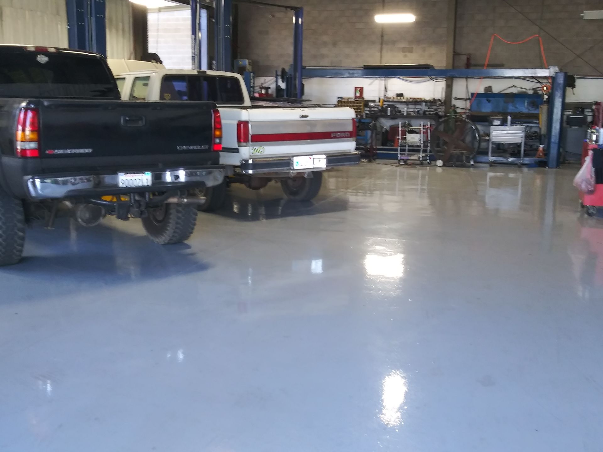 Black pickup trucks parked in an auto shop with a glossy blue floor and equipment in the background | Polar Bear Auto Care
